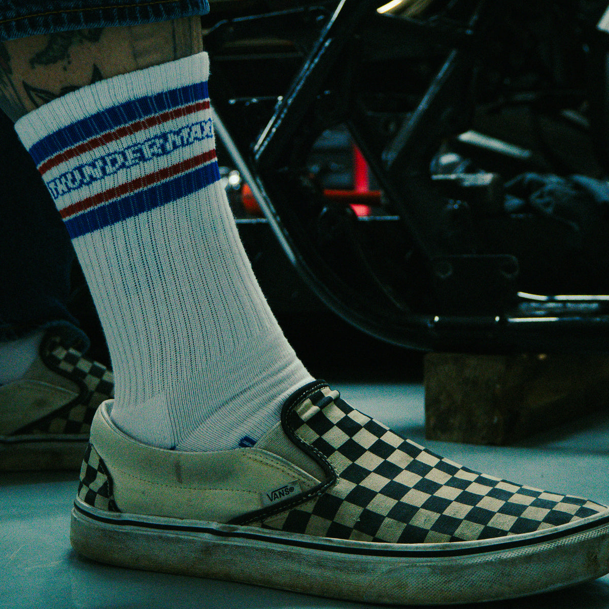 American Traditional sock with red and blue stripes worn above a checkerboard shoe