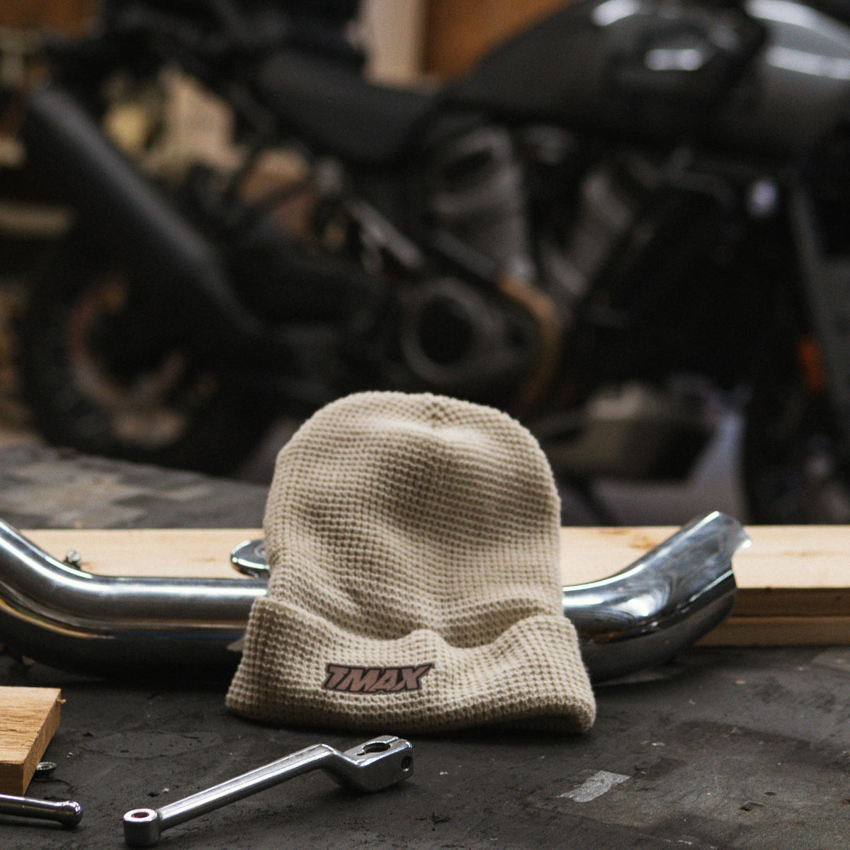 TMax Birch beanie displayed beside motorcycle parts on a workbench
