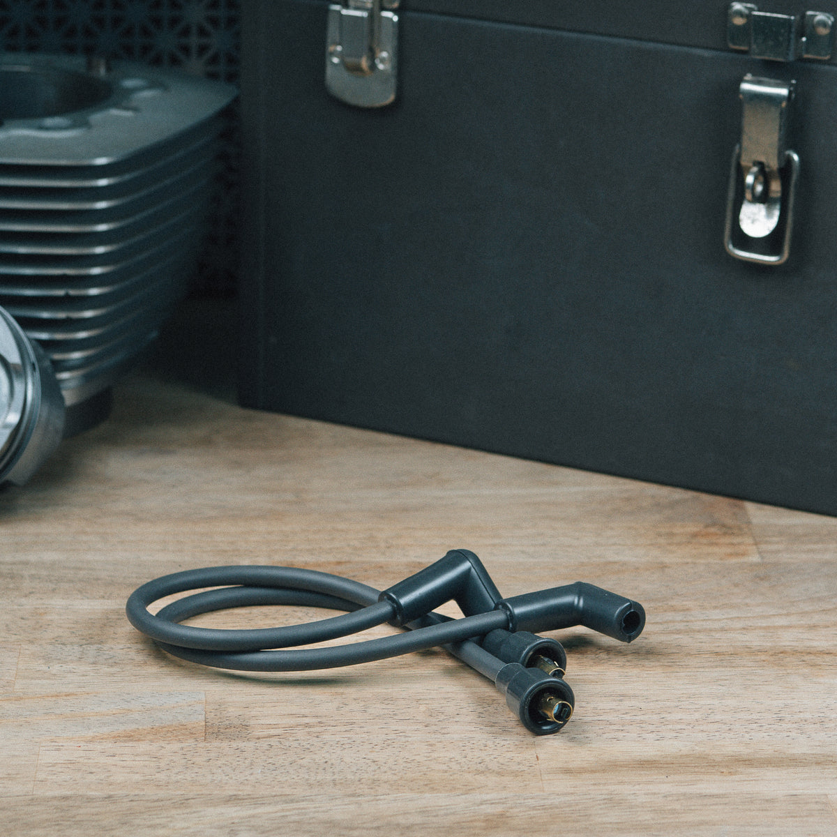 Two ignition plug wires with boots on a wooden workbench