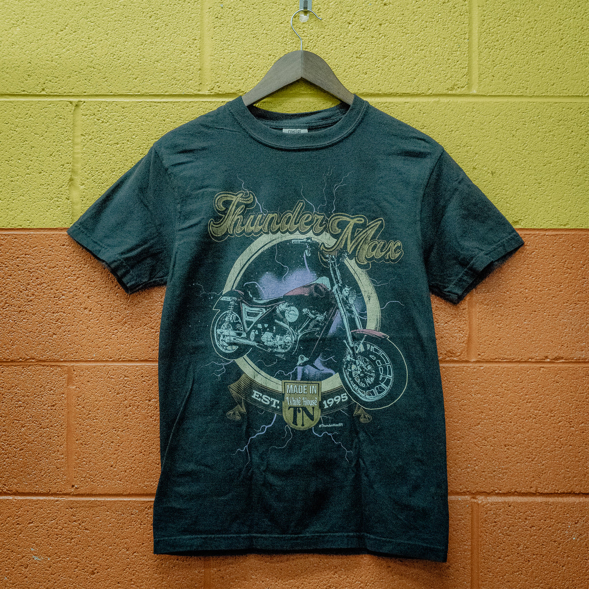 FXR Forever T-shirt hanging against a yellow and orange block wall