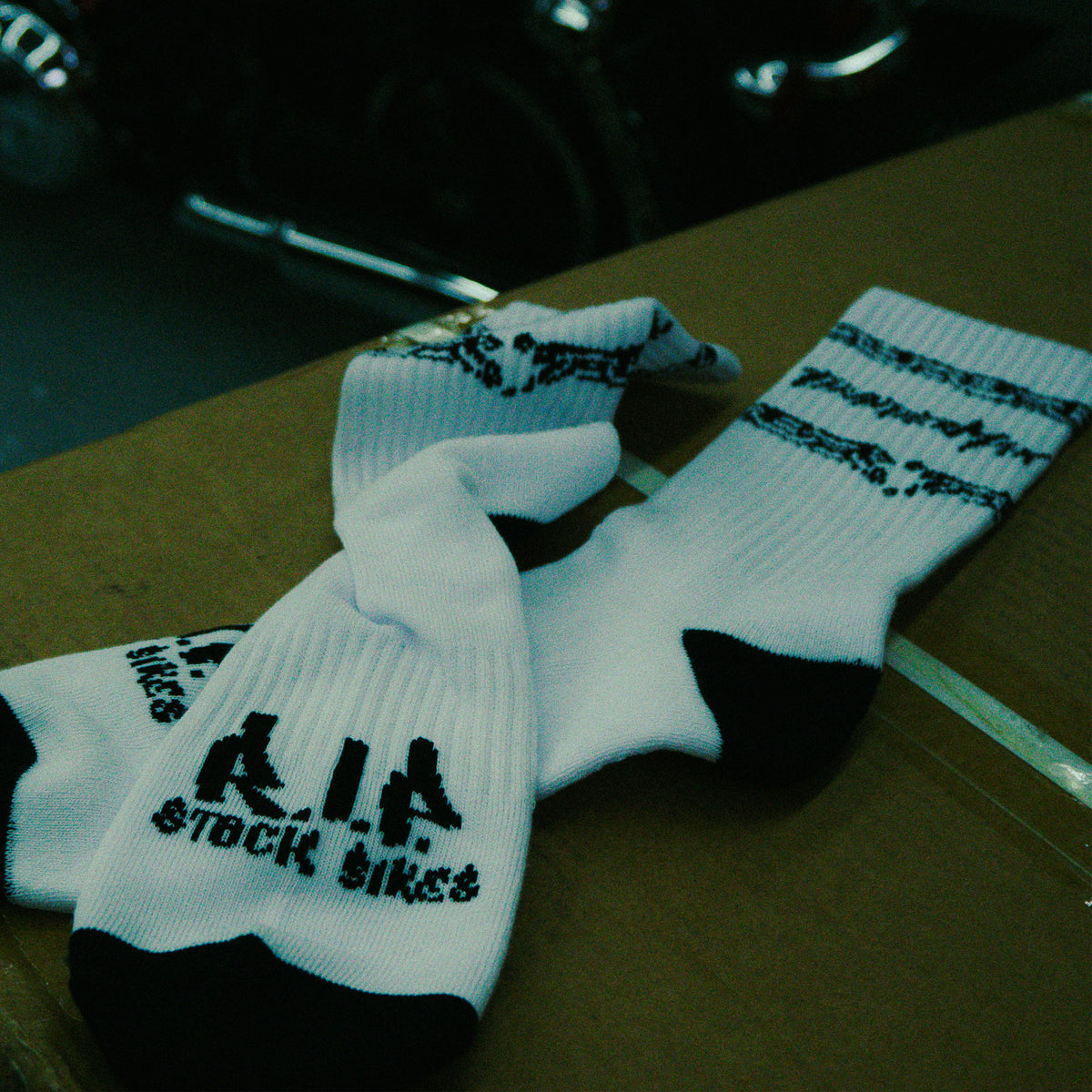 White Unchained Performance socks showing black chain graphics and R.I.P. Stock Bikes sole lettering